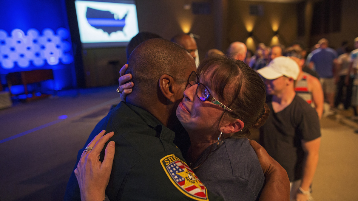 East Baton Rouge Sheriff officer Eddie Guidry is hugged by a teary Terri Carney, both members of The Rock Church which is a ministry on the outskirts of Baton Rouge, during a prayer vigil for the officers killed and wounded by a gunman on Sunday as well as members of the local law enforcement community in Zachary, La., Monday, July 18, 2016. About 100 people came to the special hour long prayer vigil. (AP Photo/Max Becherer)