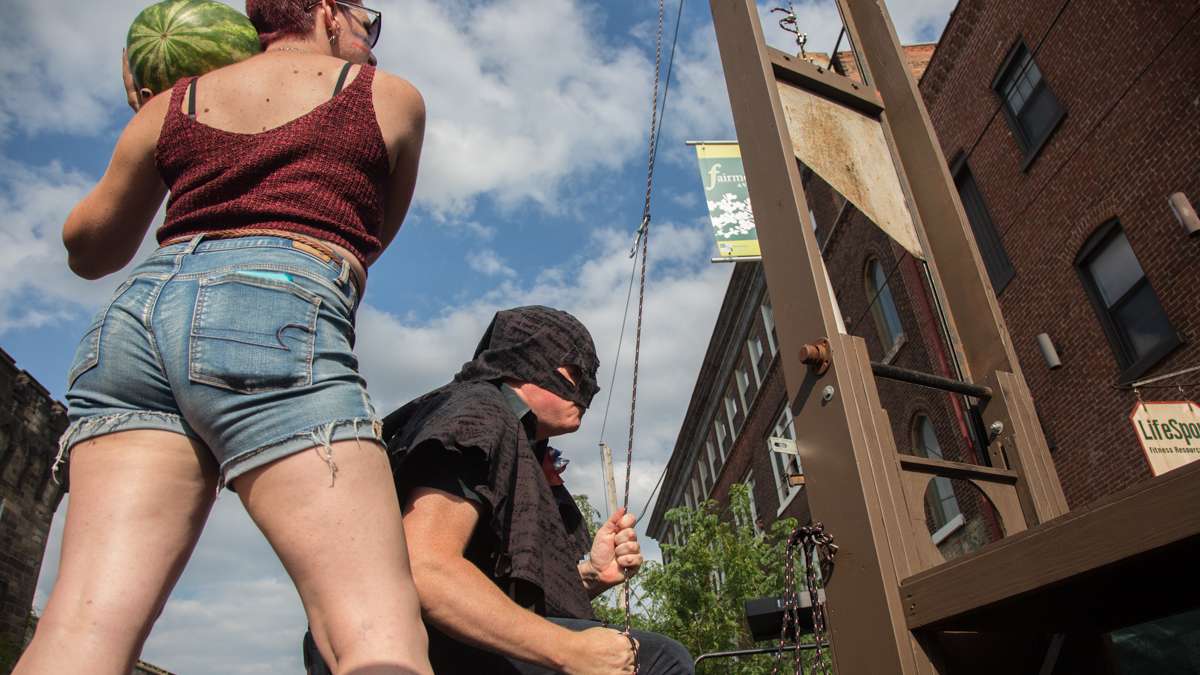 The executioner prepares the guillotine for the annual slicing of the watermelon during the Bearded Ladies Cabaret Bastille Day performance at Eastern State Penitentiary