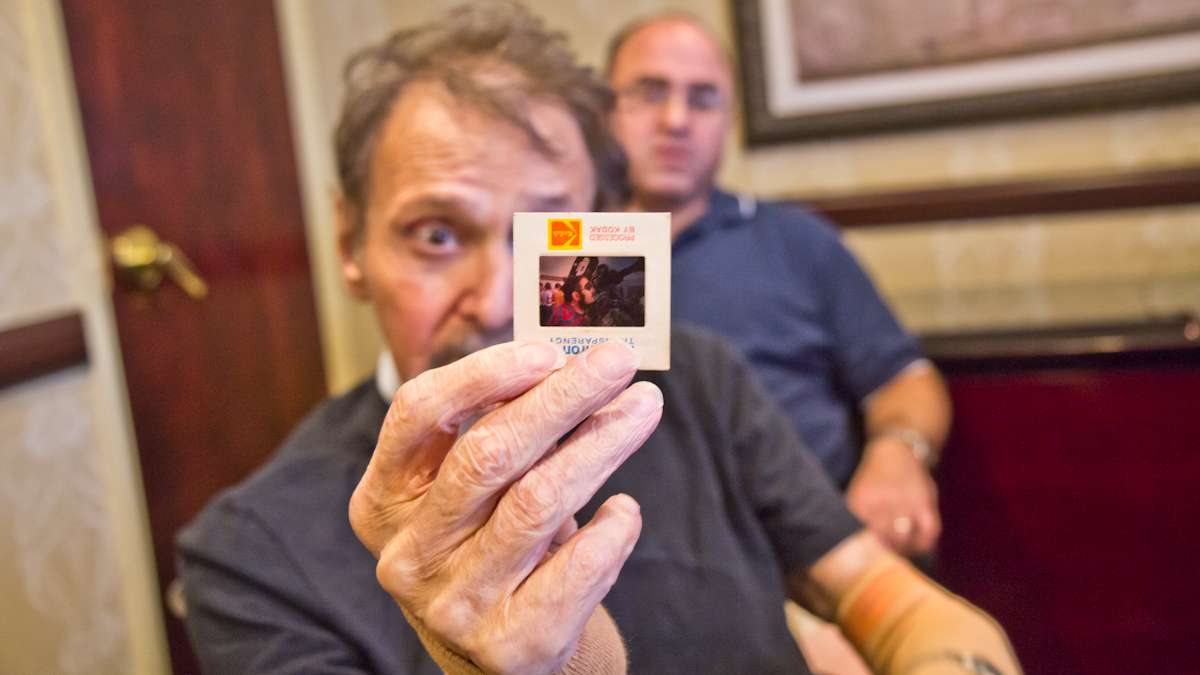 Stephen Berr holds up a slide from a cruise he and his wife took to see a total solar eclipse in Africa. (Kimberly Paynter/WHYY)