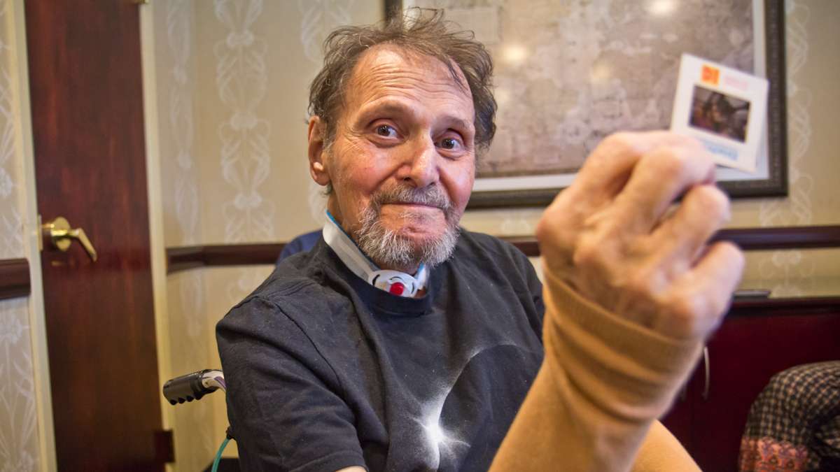 Stephen Berr holds up a slide from a cruise he and his wife took to see a total solar eclipse in Africa. (Kimberly Paynter/WHYY)
