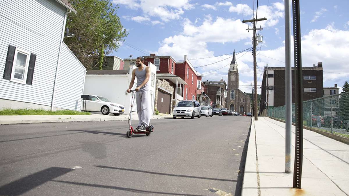 Francisco Figero, 23, rides a motorized scooter down Perry Street in South Bethlehem, Pa. (Lindsay Lazarski/WHYY)