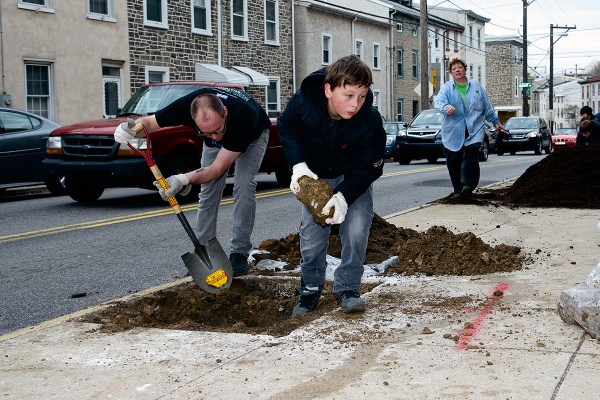 <p><p>Landen Banks removes one of many concrete blocks he found in the hole he and J.D Cramer are working on. (Bas Slabbers/for NewsWorks)</p></p>
