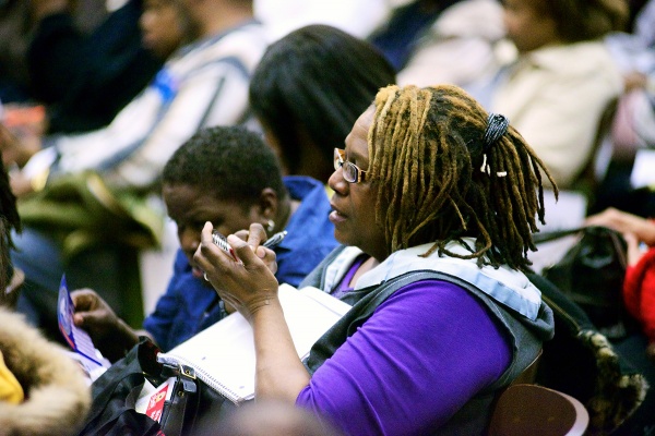 <p><p>A woman in the audience writes down information about how to apply for a job at the ShopRite. (Bas Slabbers/for NewsWorks)</p></p>
