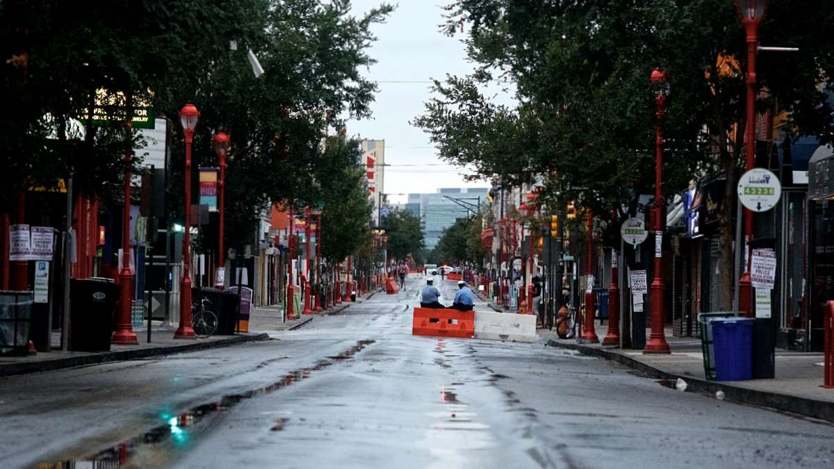 Two police officers sit on a barrier in the middle of a closed South Street, which was closed to vehicles Saturday morning.
