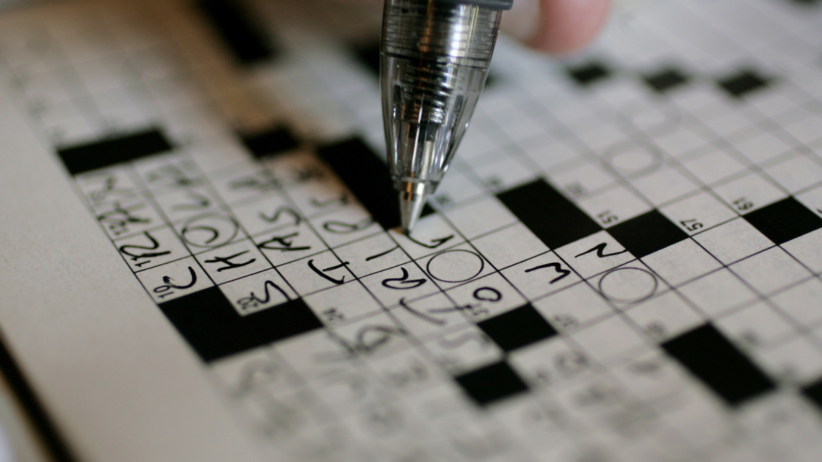  A puzzle fan works on the New York Times crossword puzzle in pen at the 