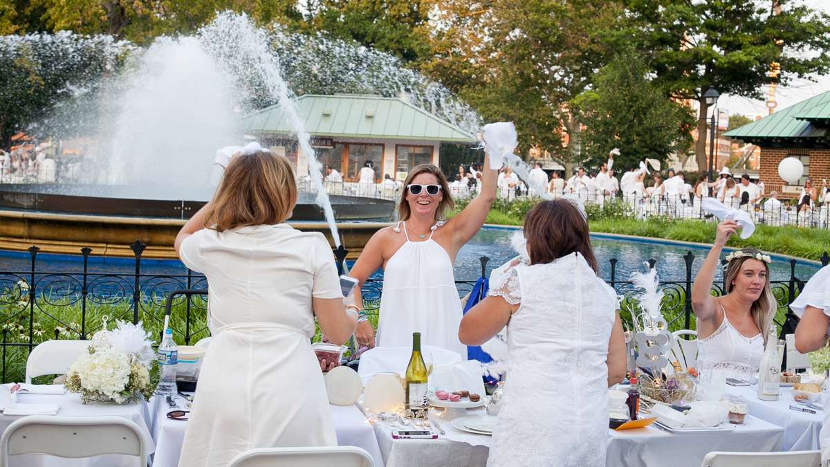 Diners wave their napkins to mark the start of Dîner en Blanc at Franklin Square. (Brad Larrison for NewsWorks)