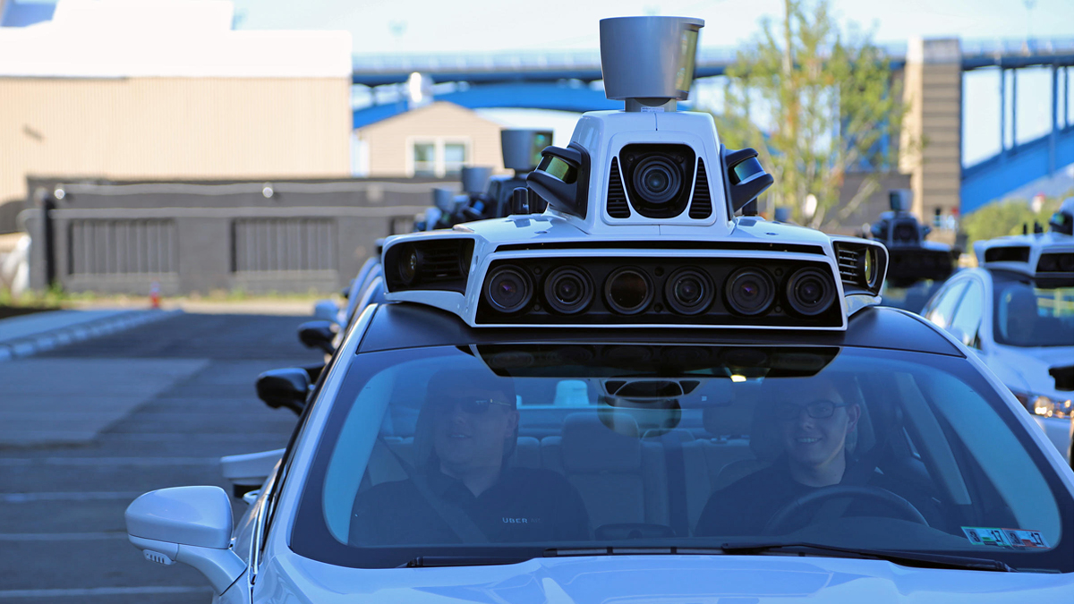 Uber technicians wait in the shadow of the company's new Advanced Technologies Center in Pittsburgh on Tuesday