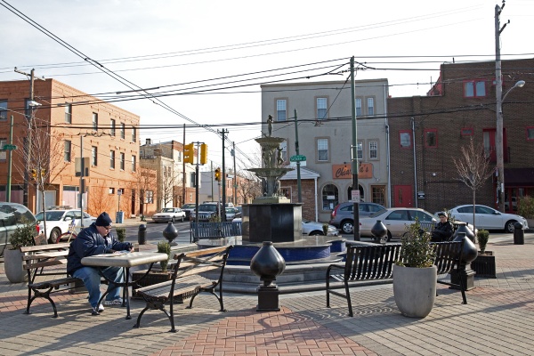 Vincent Orme (left) reads the South Philly Review at the fountain at Tasker Street and East Passyunk Avenue. (Lindsay Lazarski/WHYY).