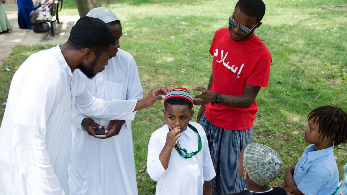 Young men admire a boy's new haircut in Clara Muhammad Square