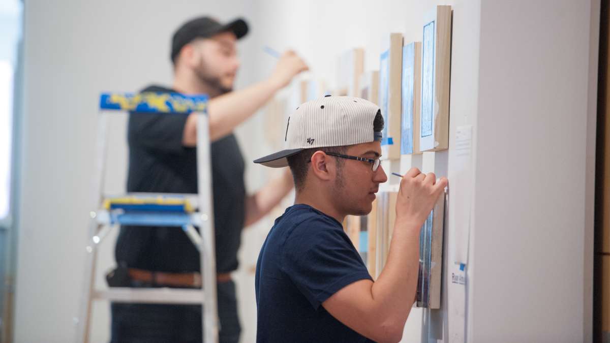 Diego Rodriguez Carrion (right) helps Ryan Almodovar install his work.