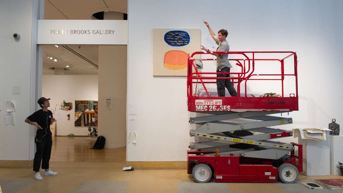 PAFA Exhibition Coordinator Brian Boutwell (right) helps student Leon Wen Xu with his installation. The painting on the wall is by Liza Samuel.