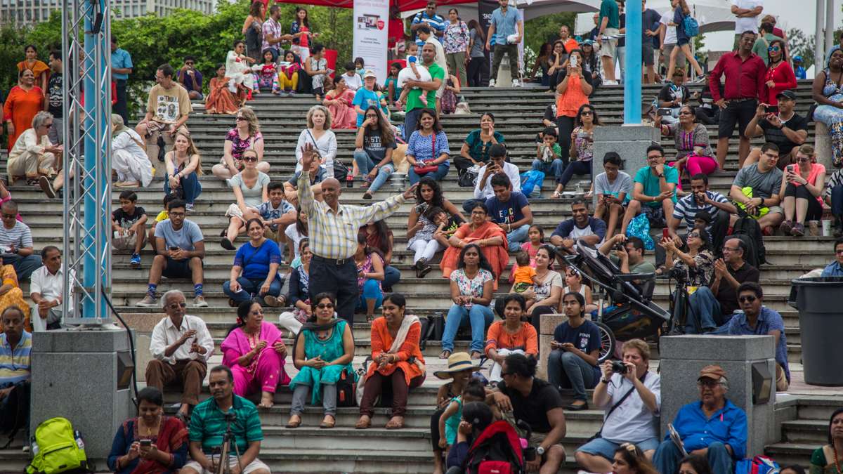 A man dances in the crowd while balancing a water bottle on his head during the Festival of India Independence Day celebration at Penn’s Landing. (Emily Cohen for NewsWorks)
