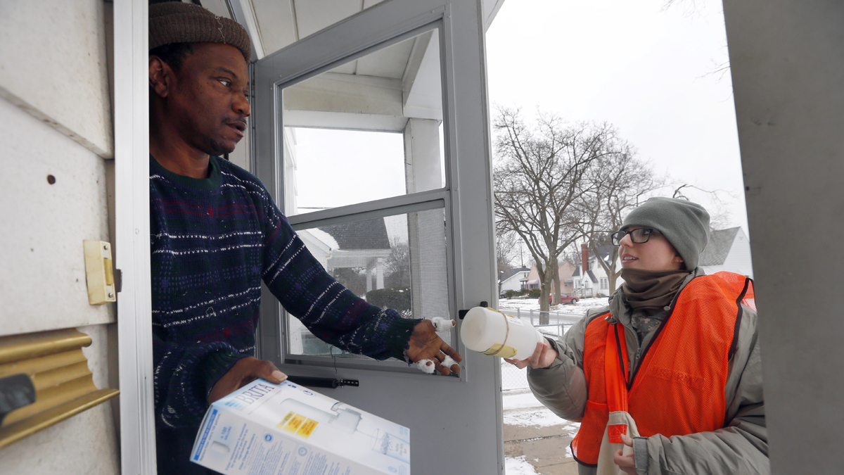  Louis Singleton receives water filters and a test kit from Michigan National Guard Specialist Jelena Tasevska Thursday, Jan. 21, 2016 in Flint, Mich. The National Guard, state employees, local authorities and volunteers have been distributing lead tests, filters and bottled water during the city's water crisis. (AP Photo/Paul Sancya) 