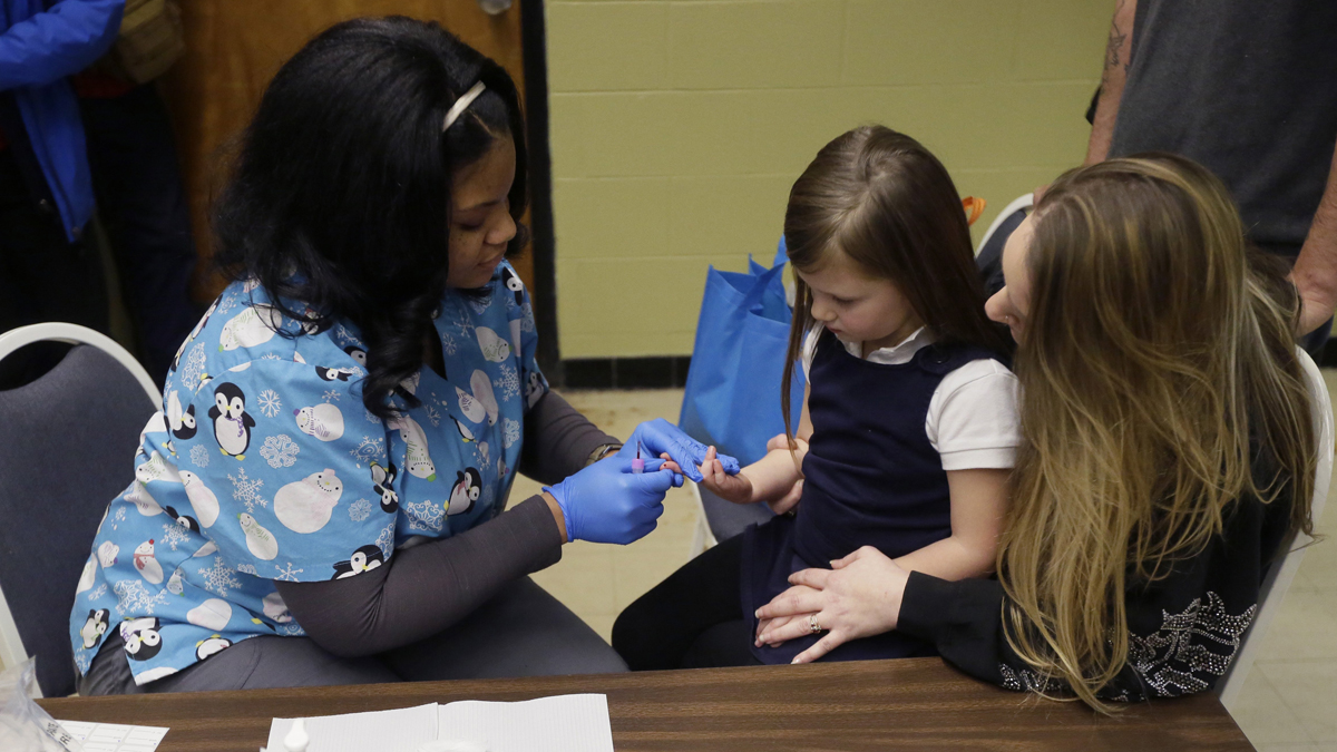 A certified medical assistant draws a blood sample from Nyla Hopper