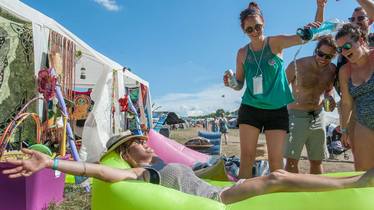 Brooke Murray stretches out on an inflatable cushion in the campgrounds while Kathleen Shaw pours water on her.
