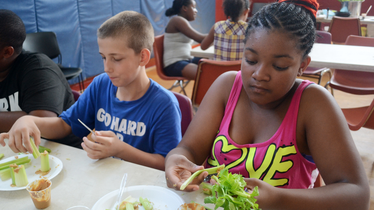  Two North Light summer campers create ants on a log as part of the new healthy eating program. (Maanvi Singh/for NewsWorks) 