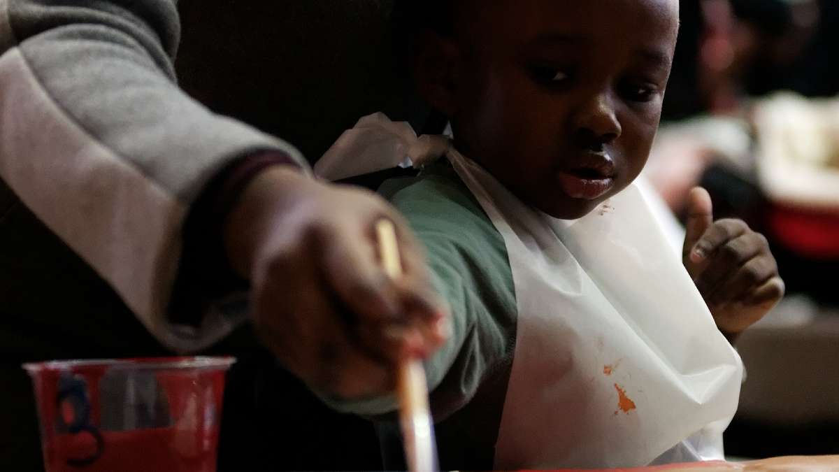 A young volunteer helps paint at the Mural Arts table. (Bastiaan Slabbers/for NewsWorks)