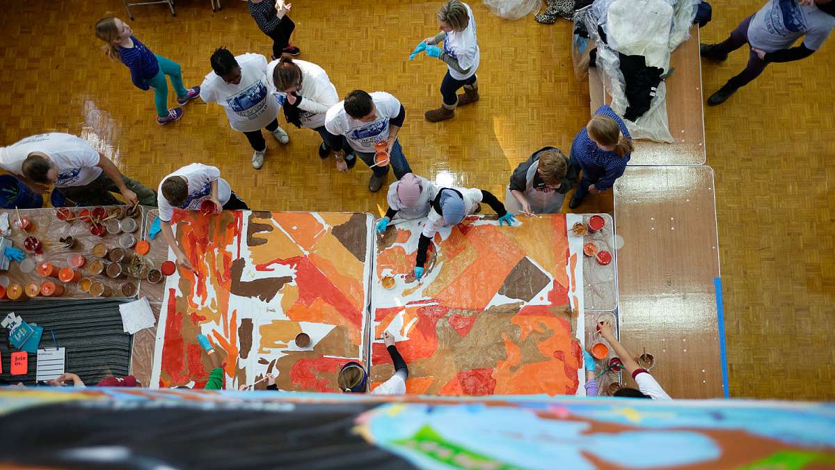Volunteers help paint canvasses for a Mural Arts project. (Bastiaan Slabbers/for NewsWorks)