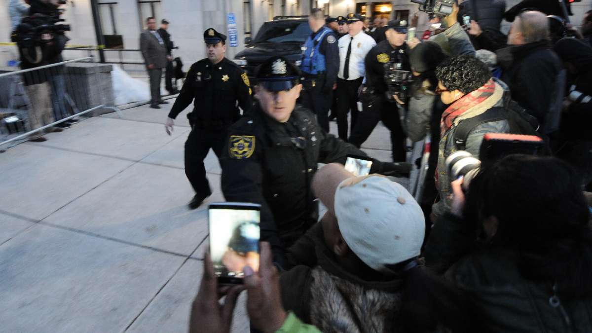 Police try to clear the sidewalk as the black SUV carrying Cosby leaves shortly after the hearing is adjourned for the day.