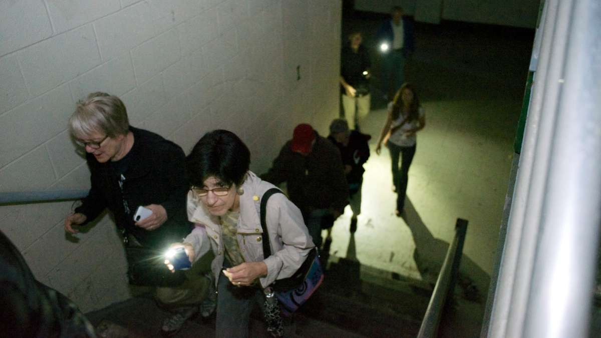 The group makes its way through the 355,000-square-foot facility with the help of mobile-phone flashlights. (Bas Slabbers/for NewsWorks)
