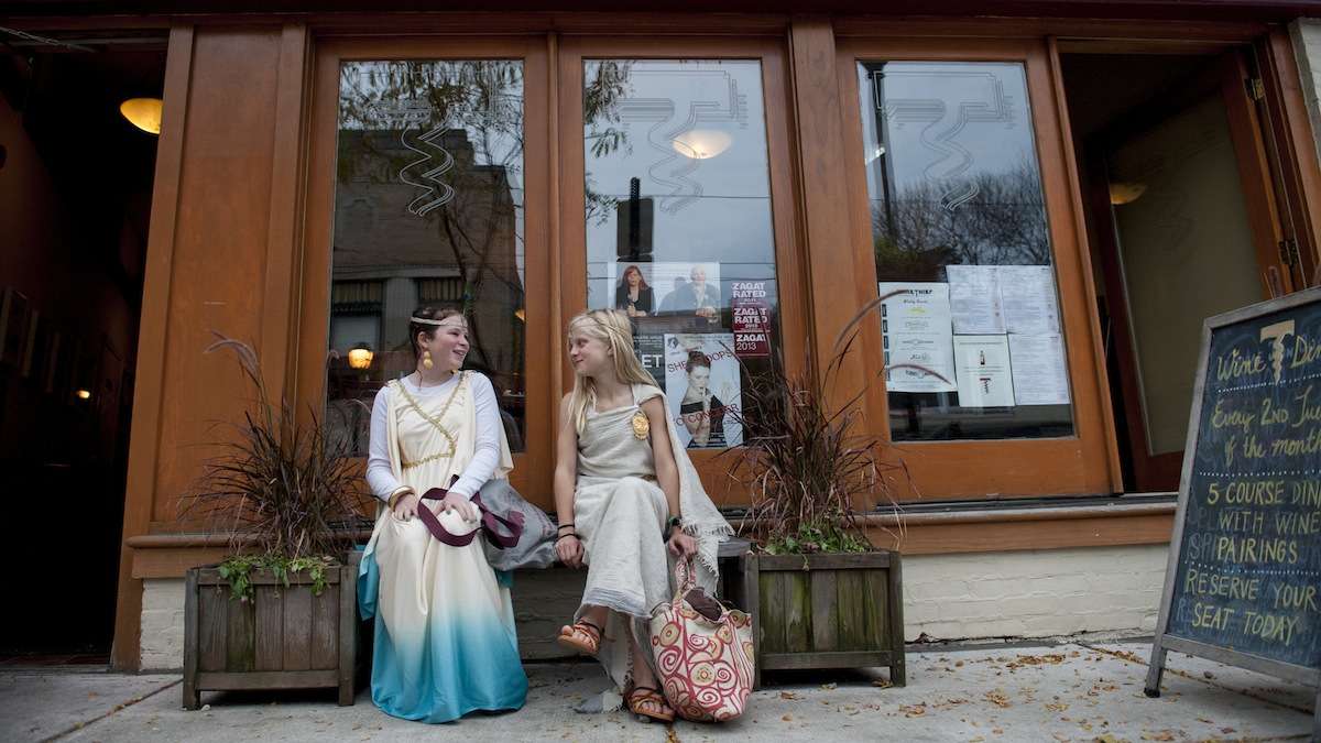 Ruby Simpson (left), 10, of Mt. Airy, and Kaya Sterner, 10, of Chestnut Hill, take a break from trick-or-treating on Germantown Avenue on Halloween evening. (Tracie Van Auken/for NewsWorks)