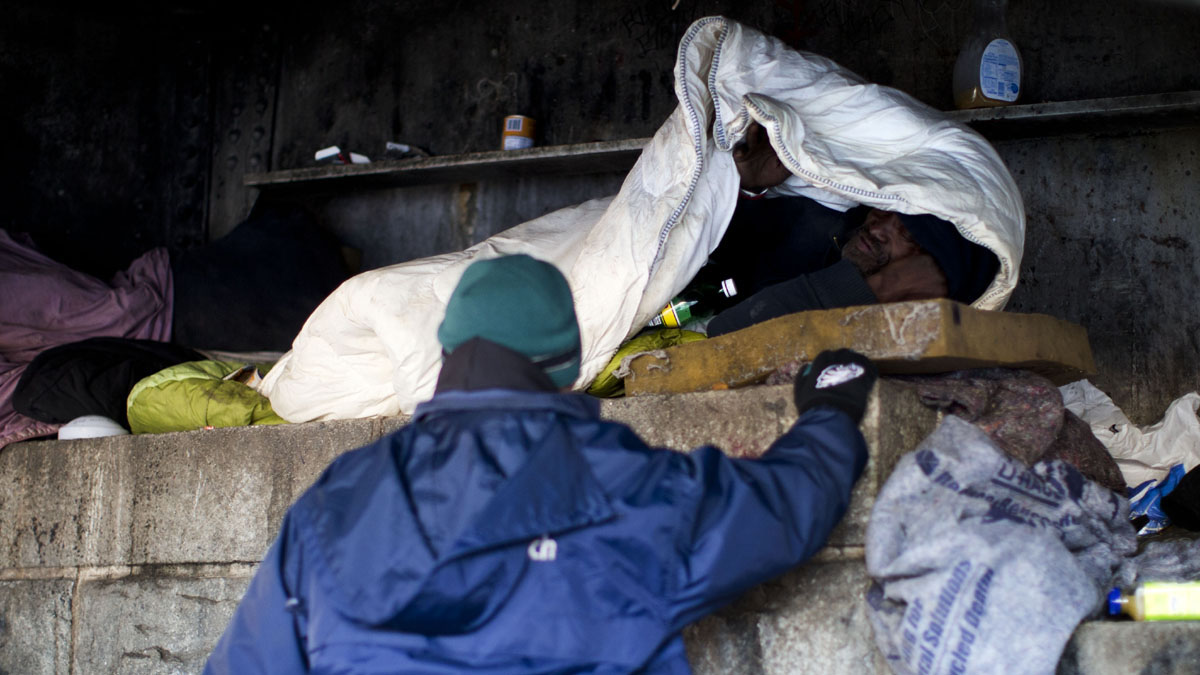  Project H.O.M.E. Outreach Response Worker Sam Santiago, center, assisting a homeless man sleeping under a bridge in Philadelphia.  (AP Photo/Matt Rourke) 