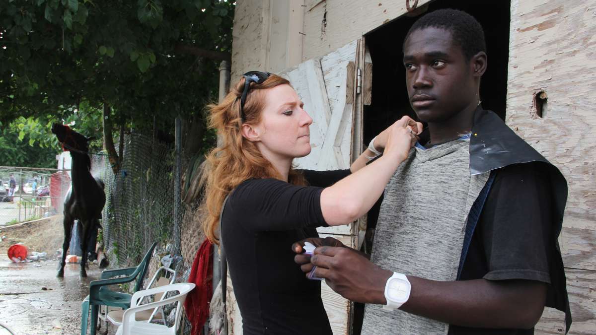Artist Jes Gamble fits rider Derrick Allen with the outfit he will wear during the horse tuning. (Emma Lee/WHYY)