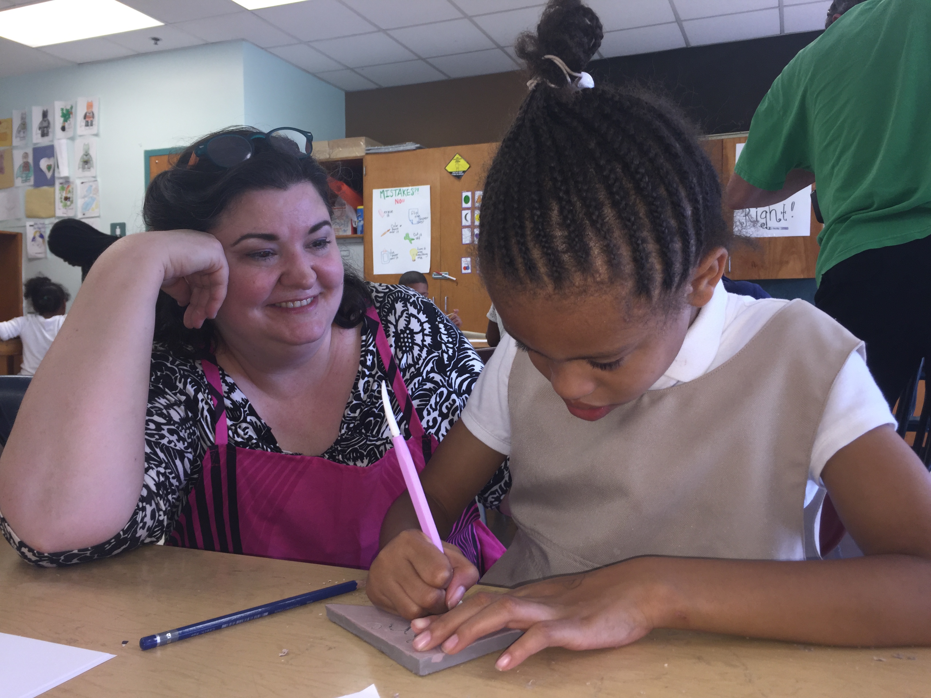  Tiernan Alexander of the Creative Vision Factory works with a student at Stubbs on the tile mosaic mural that will be installed in the lobby this summer. (Cris Barrish/WHYY) 