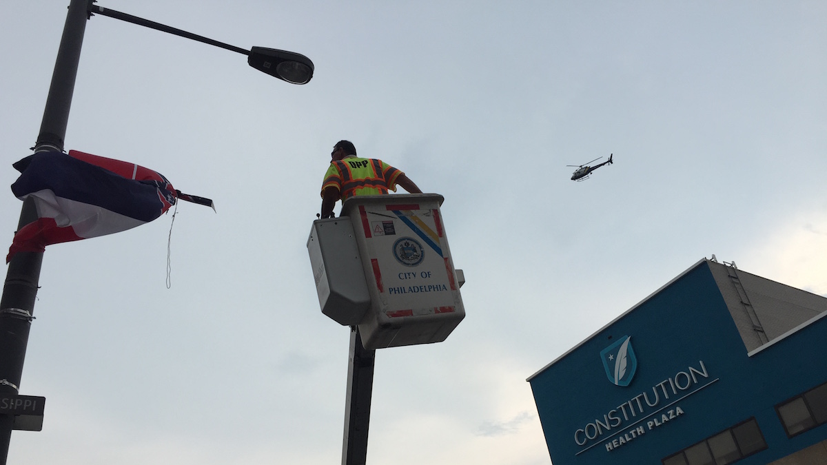  A city worker rises to the Mississippi state flag to take it down following calls from protesters for the flag featuring a Confederate symbol to be removed. (Bobby Allyn / WHYY) 