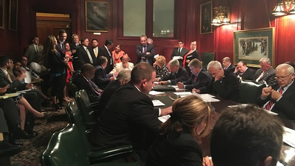  State Senators and staffers huddle in a committee meeting room. (Katie Meyer/WITF) 