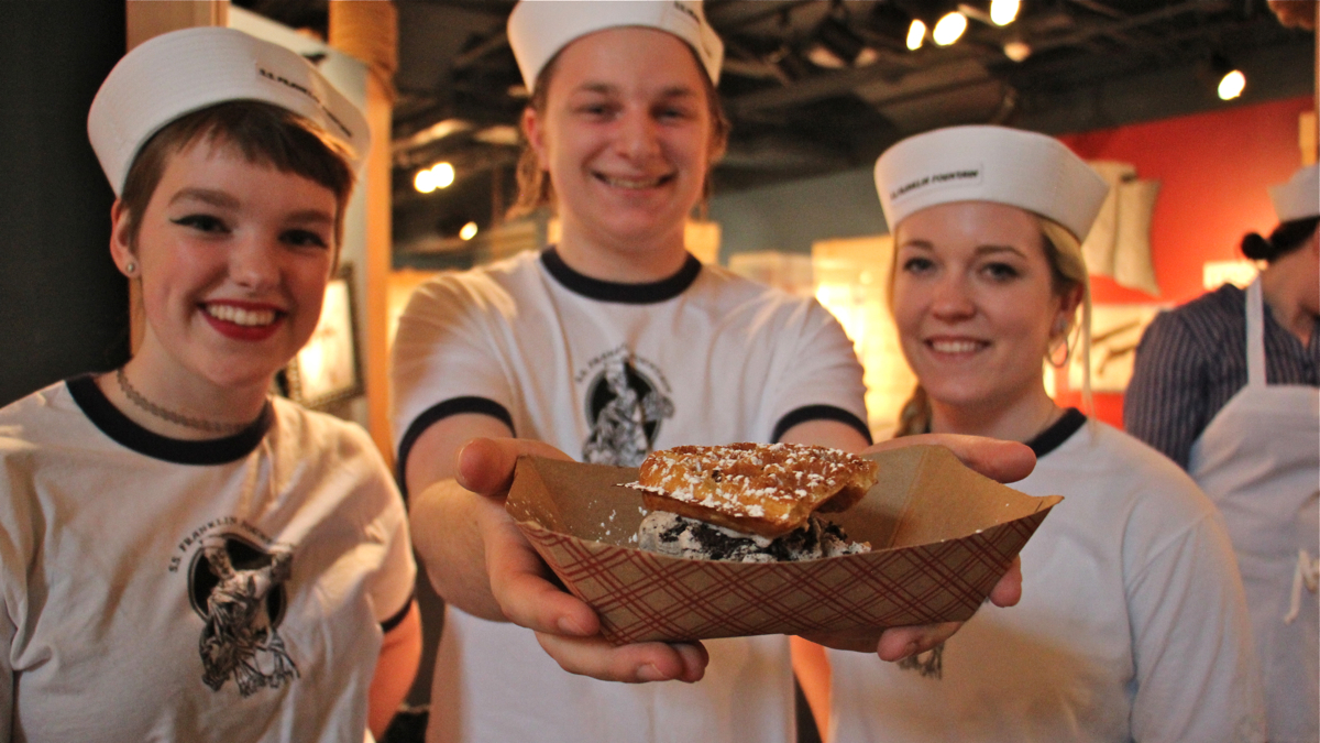 Chloe Howard, Nick Cioppi, and Maddy Pelish of Franklin Fountain serve up a waffle ice cream sandwich, such as will be served at the S.S. Franklin Fountain at Spruce Street Harbor Park. (Emma Lee/WHYY)