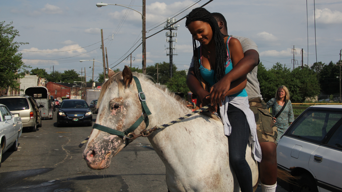  Dajah Thomas, 16, gets a ride down Fletcher Street on Lou Fletcher's horse, Montana. (Emma Lee/WHYY) 
