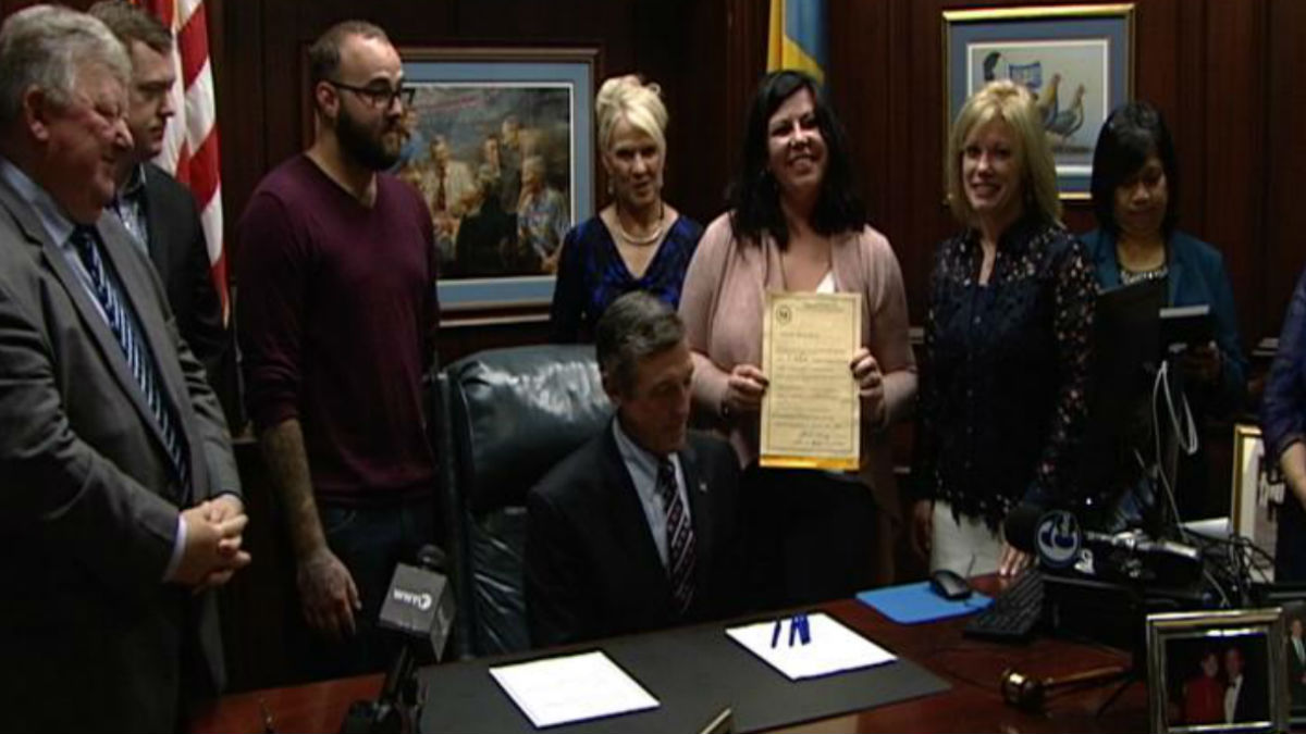  Kim DiSalvo holds Lorenzo's law after it was signed by Gov. John Carney in his Wilmington office.(Dan Rosenthal/WHYY) 