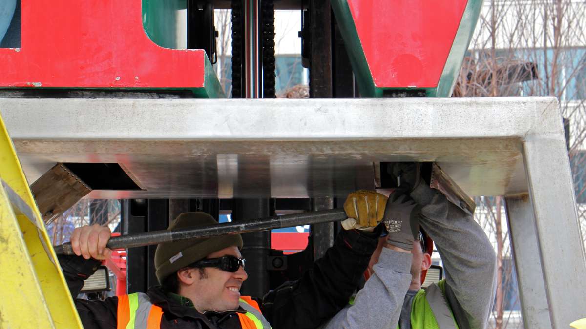 Workmen struggle with stubborn bolts on the LOVE statue, which has not been disassembled for nine years.