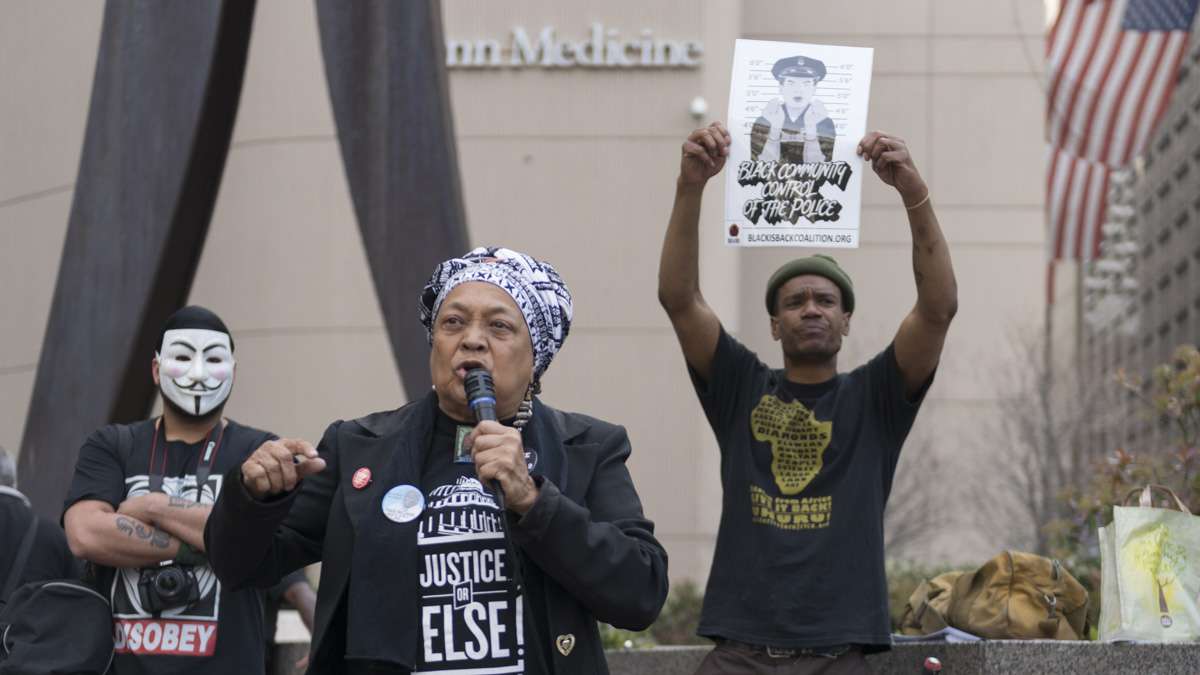 Pam Africa is flanked by a masked member of the group Anonymous and Diop Olugbala. (Branden Eastwood for NewsWorks)
