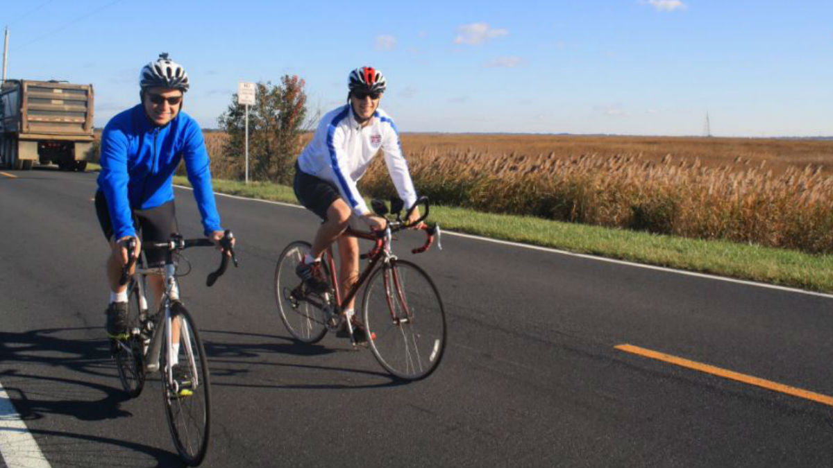  Then-Gov. Jack Markell (in blue) bikes along Rt. 9 near Port Penn in November with WHYY's Mark Eichmann.(File/WHYY) 