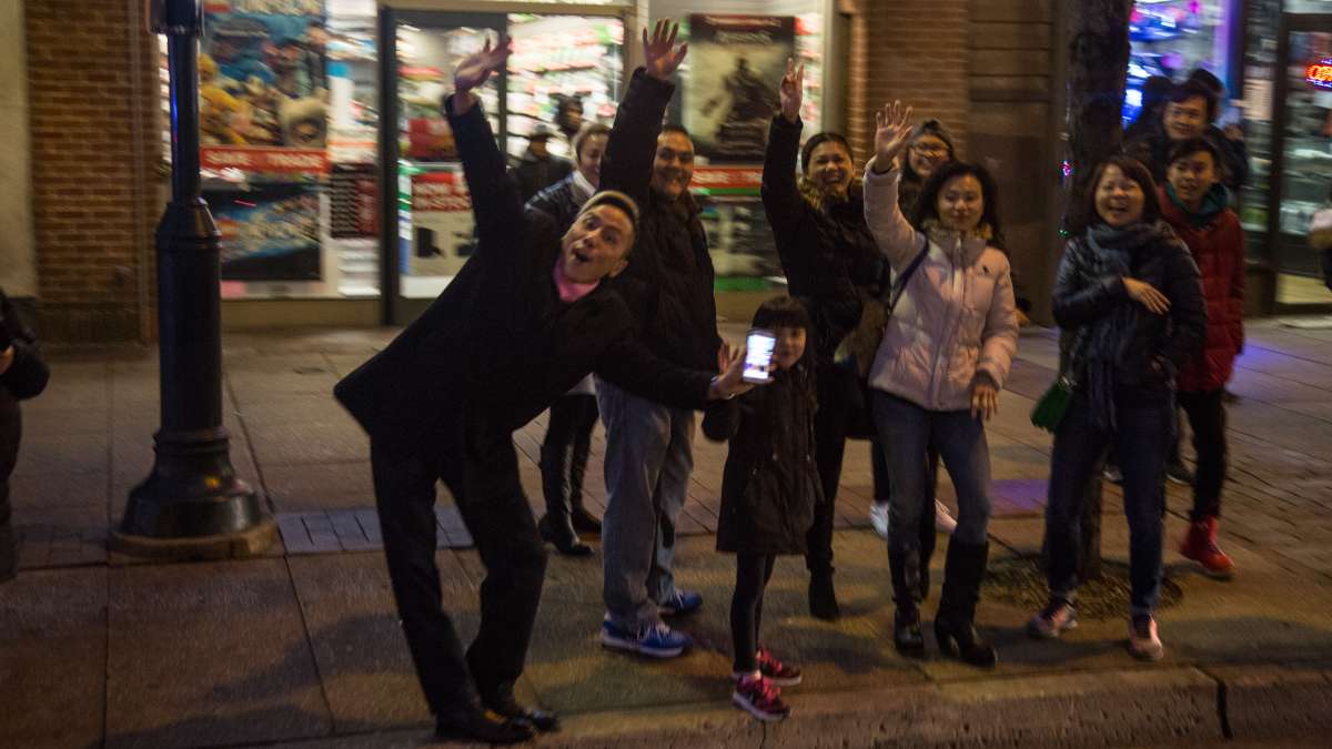 Spectators wave and cheer as the parade passes through Center City on its way to Independence Mall.