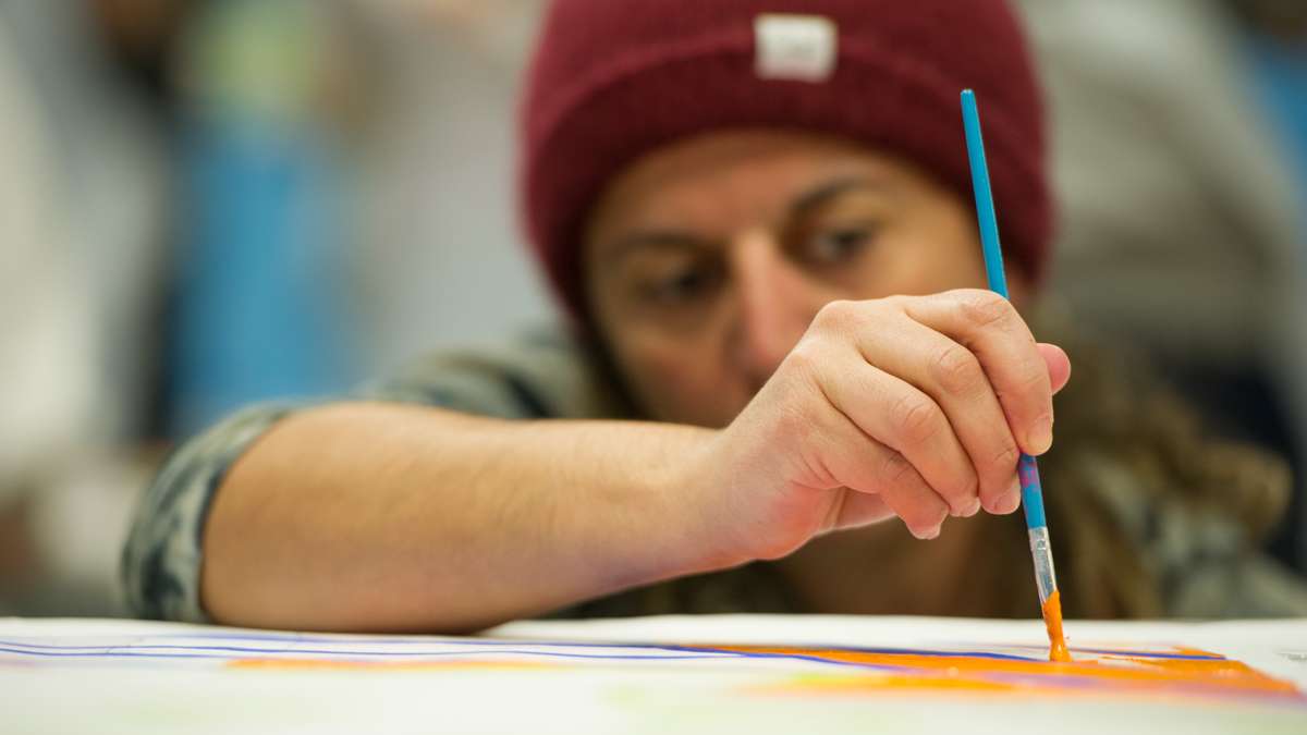 Rima Jacobs carefully applies paint to one of the canvas squares.