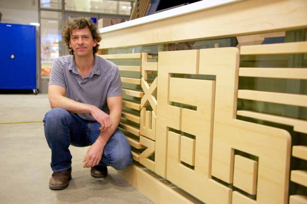 <p><p>Evan Malone, president and co-creater of NextFab, crouches down next to the new front desk of NextFab. (Nat Hamilton/for NewsWorks)</p></p>
