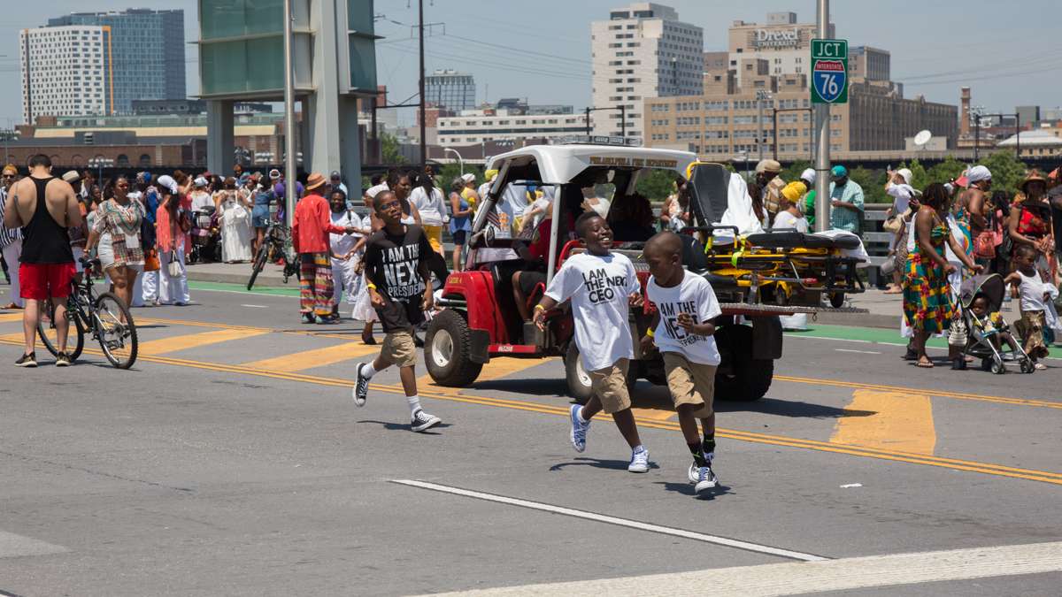 (From left) Niya Ogundana, 12, Bayo Ogundana, 9, and Chase Brown, 9, run around the South Street bridge after the religious ceremony at the beginning of the Philadelphia Odunde Festival.
