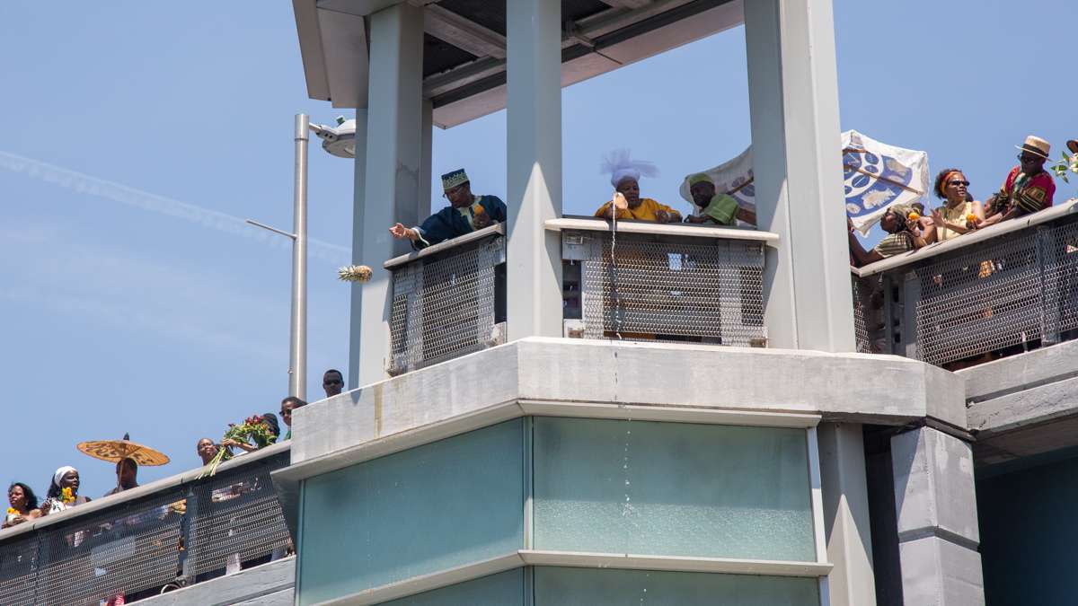 Celebrants toss fruit and honey into the Schuylkill River as an offering to the river goddess Oshun to start the Philadelphia Odunde Festival.