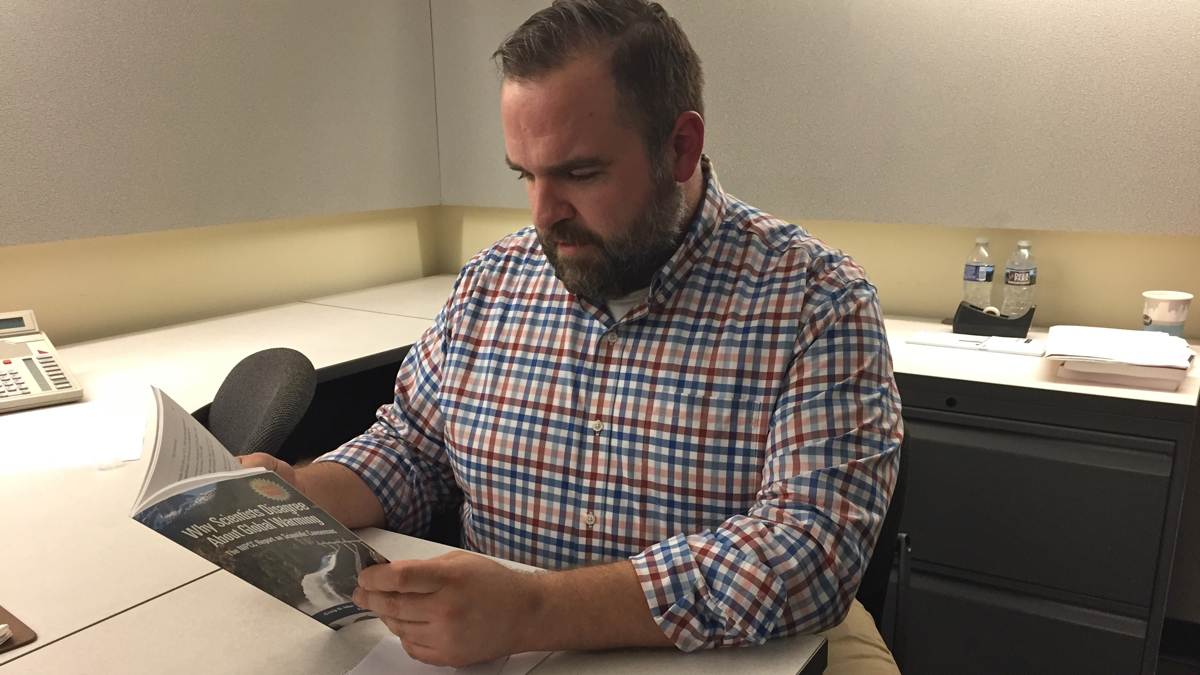  Science teacher Patrick Engleman looks through a Hartland Institute publication, ''Why Scientists Disagree About Global Warming.'' (Avi Wolfman-Arent/WHYY) 