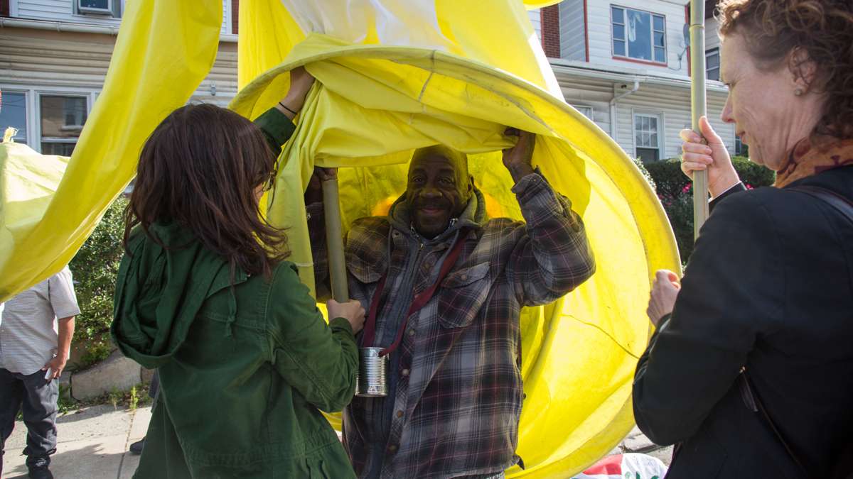 A member of the Girard Medical Center coalition steps out from under a massive puppet he and his fellow recoverers made for the 17th annual Peoplehood parade in West Philadelphia, October 29th 2016. (Emily Cohen for NewsWorks)
