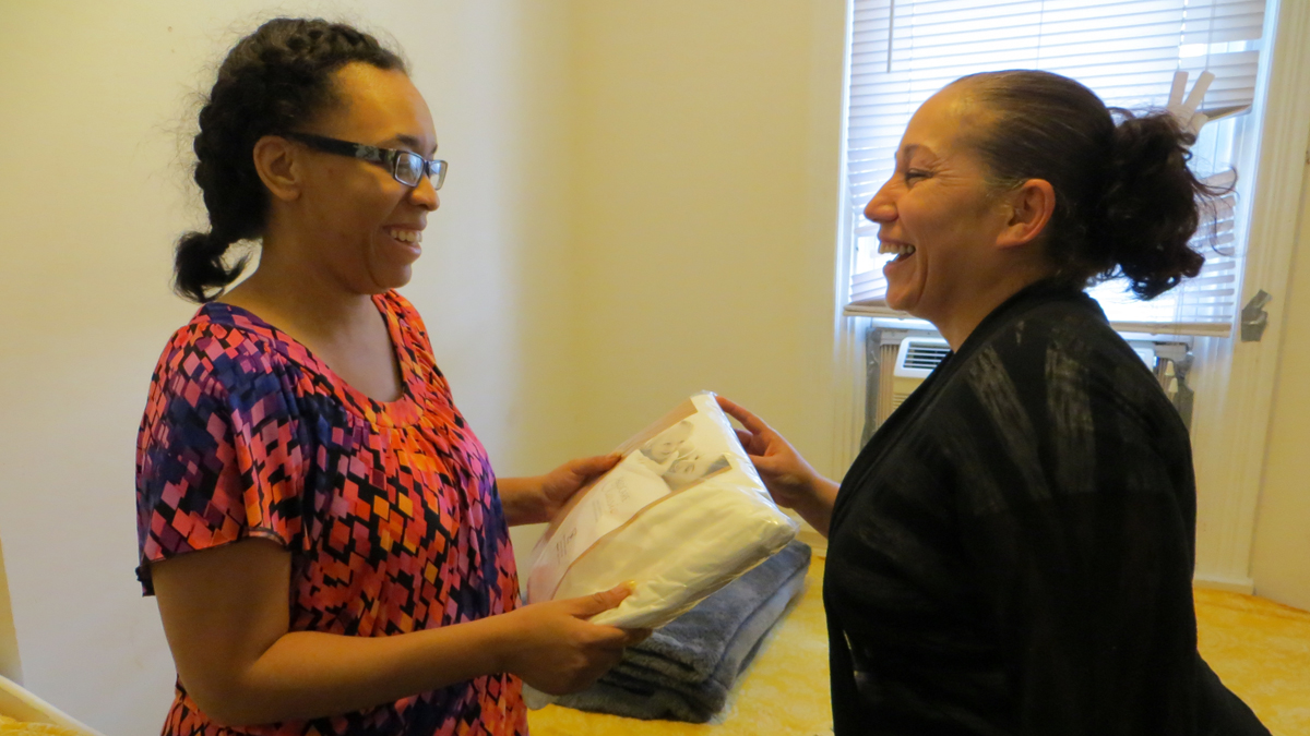  Carmen Perez, of the Children's Hospital of Philadelphia's Community Asthma Prevention Program, gives Victoria Harris mattress covers and a special pillowcase for her children. (Taunya English/WHYY) 