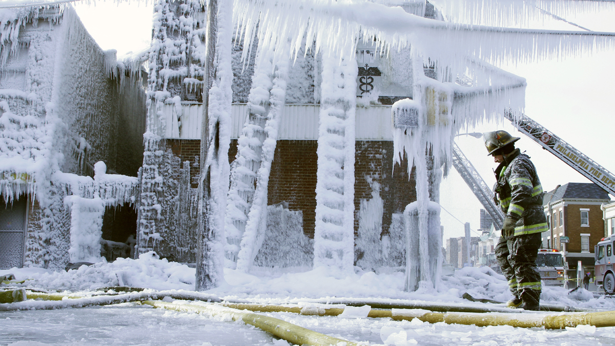  A Philadelphia firefighter walks near the scene of an overnight blaze in west Philadelphia, where ice has formed from the water used to fight the fire. Bone-chilling, single digit temperatures have gripped the region. (AP Photo/Jacqueline Larma) 