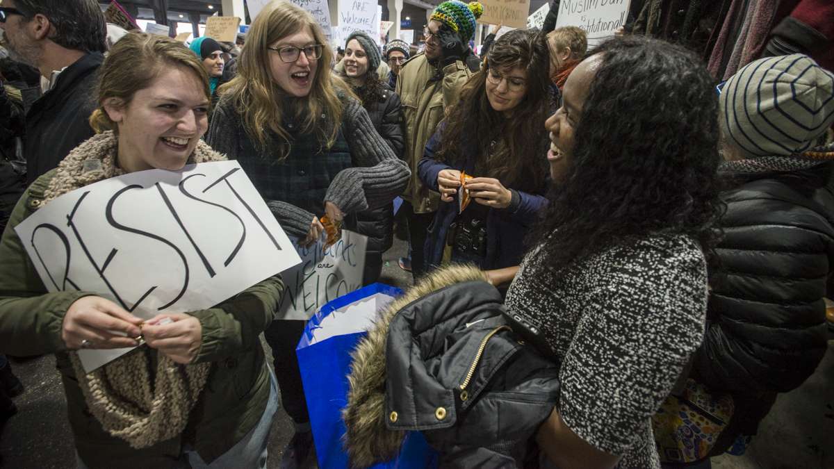 (From left) Hannah Zieve, June Freifelder, and Katie Levesque take snacks brought to the protest by Charece Collines. Collines said she had been in similar situations and knows that sometimes people need a snack. (Branden Eastwood for NewsWorks)