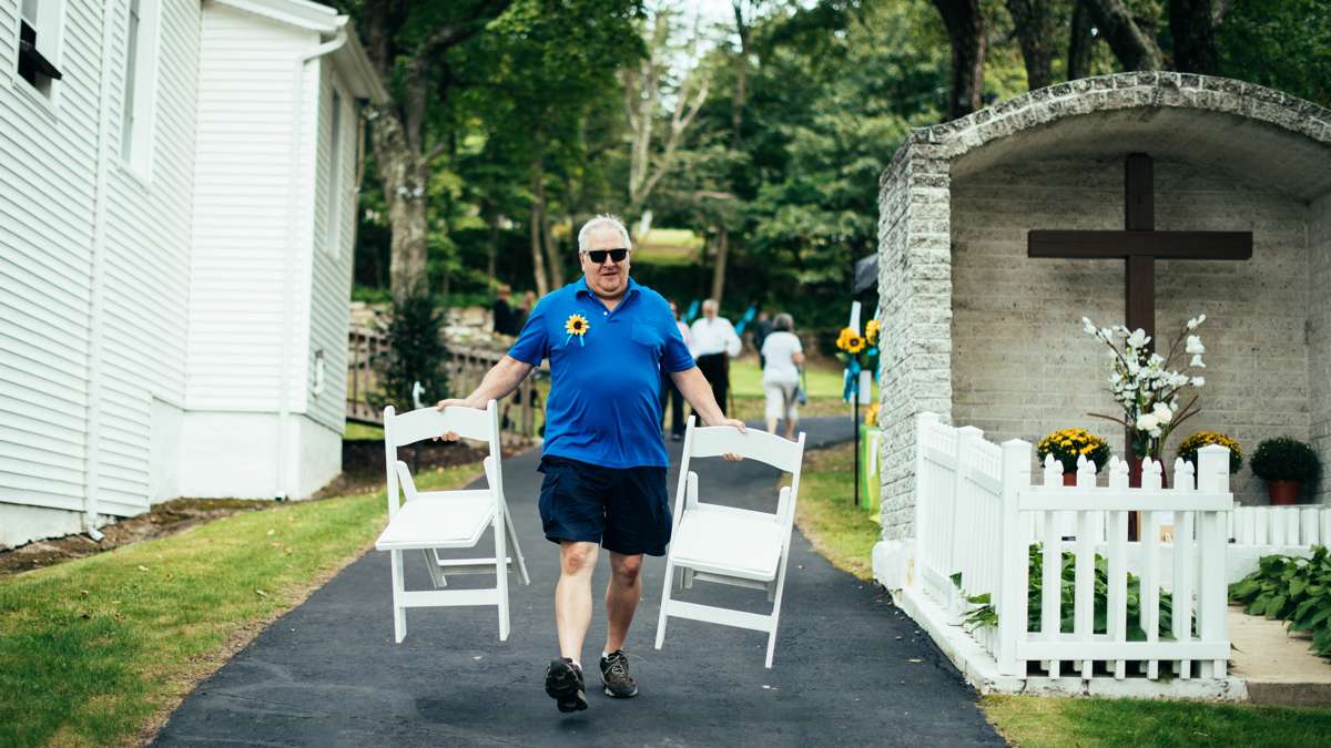 Mike Pesarchick, a member of Ss. Peter & Paul in Mount Carmel, brings chairs to accomidate more pilgims on the lawn during Divine Liturgy.