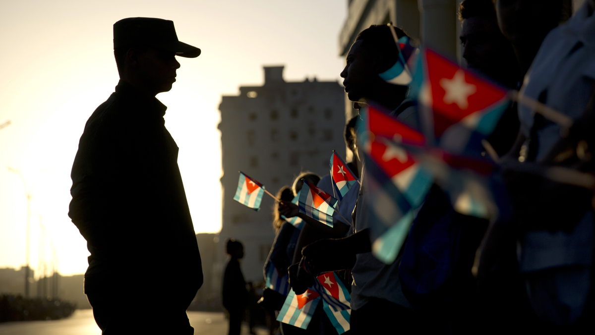  A soldier is silhouetted against the early morning sky as people holding Cuban flags wait for the motorcade transporting the remains of Cuban leader Fidel Castro in Havana, Cuba, Wednesday, Nov. 30, 2016. Castro's ashes have begun a four-day journey across Cuba from Havana to their final resting place in the eastern city of Santiago. (AP Photo/Natacha Pisarenko) 