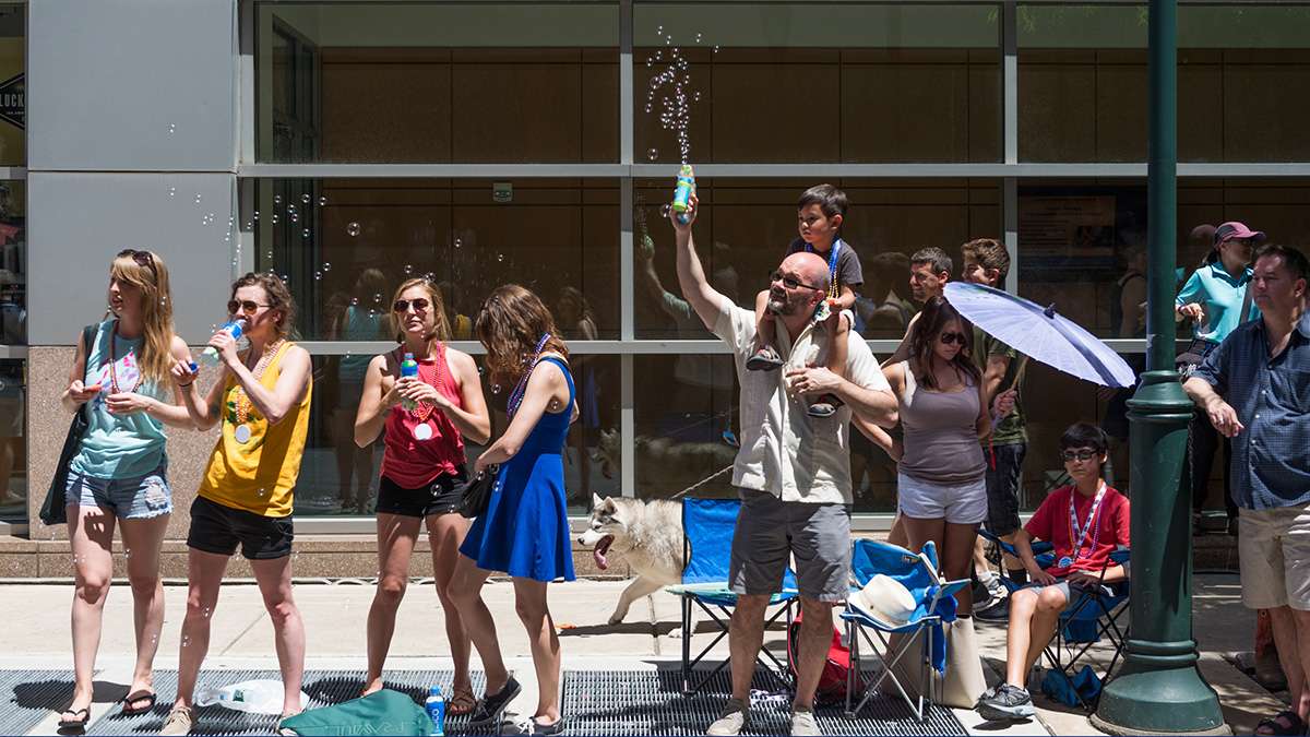 Brian Morris carries a bubble gun and his son Max along the Pride parade route in Philadelphia. (Branden Eastwood for NewsWorks)