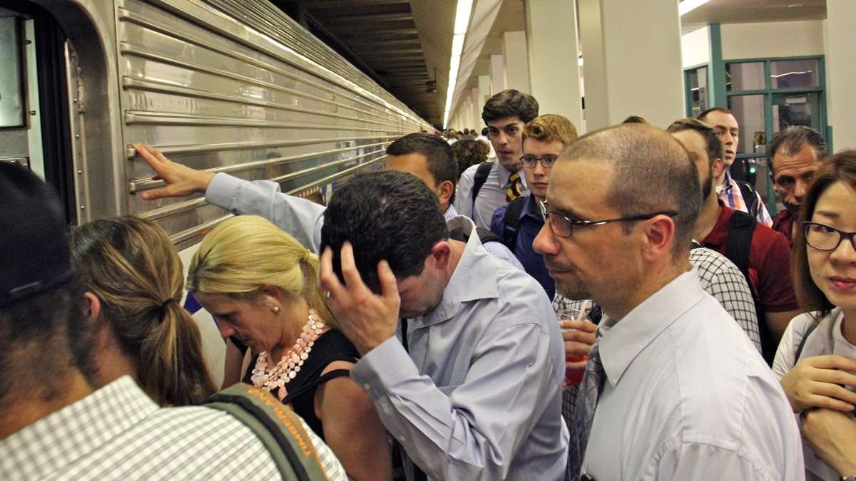 Boarding passengers form a crush at the door to a regional rail car during the evening commute. (Emma Lee/WHYY)